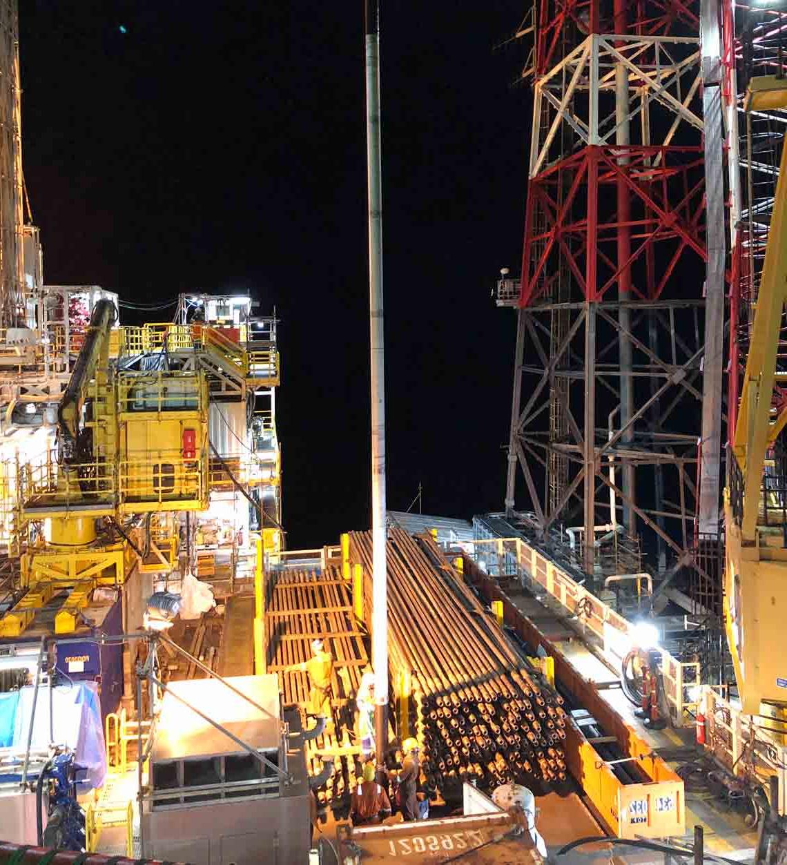 Rig floor at night with a crane lifting one of the expandable steel patches used for casing repair.  