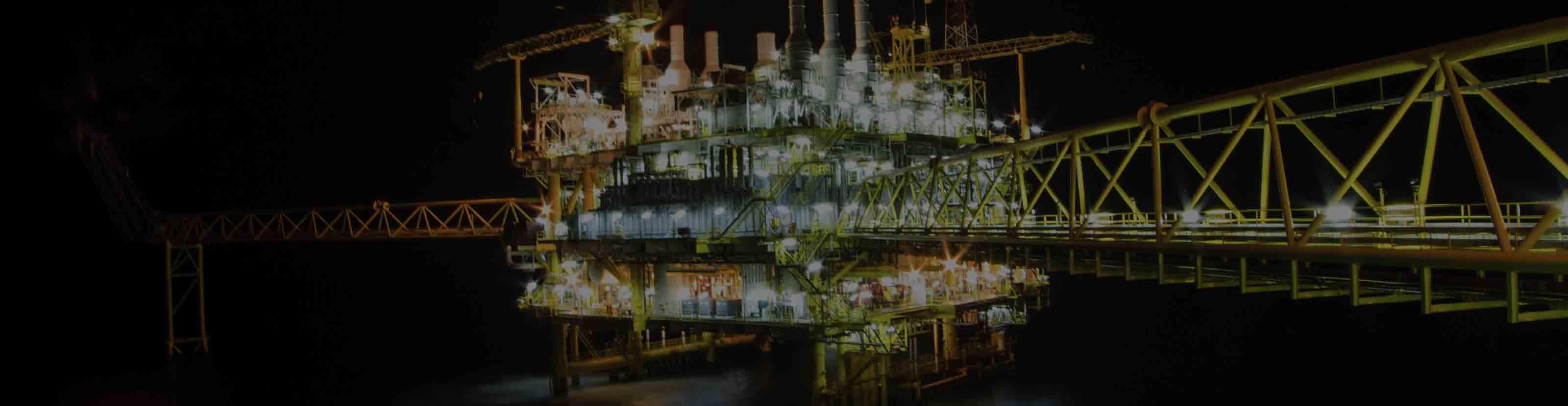 A brightly lit offshore drilling and production platform at night