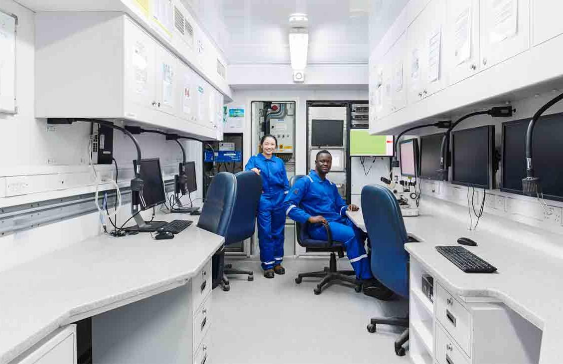 在移动实验室里穿着蓝色工作服的工作人员的照片