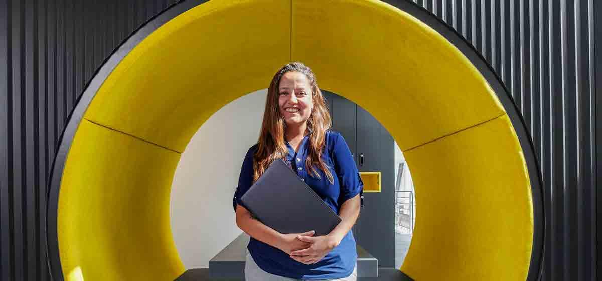 Woman standing in front of a yellow tunnel in an office building (Tier 1_Office_Clamart_OAT_0350)