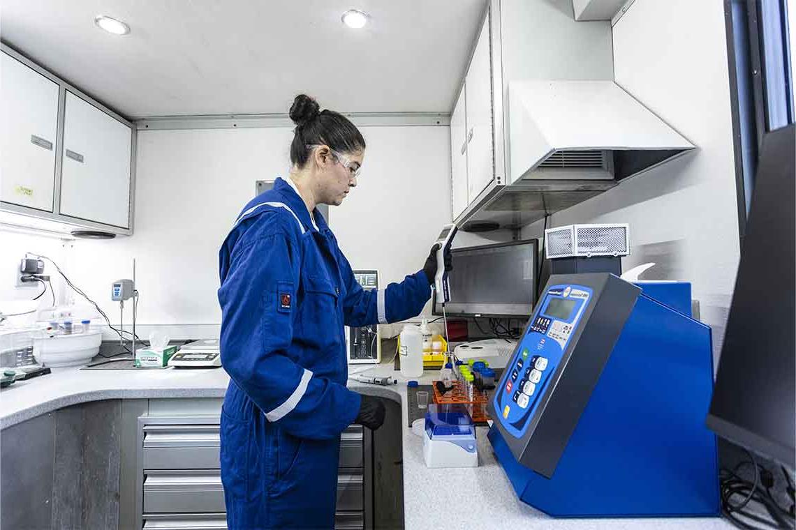 实验室里穿着蓝色工作服的女人用探针检测充满液体的试管