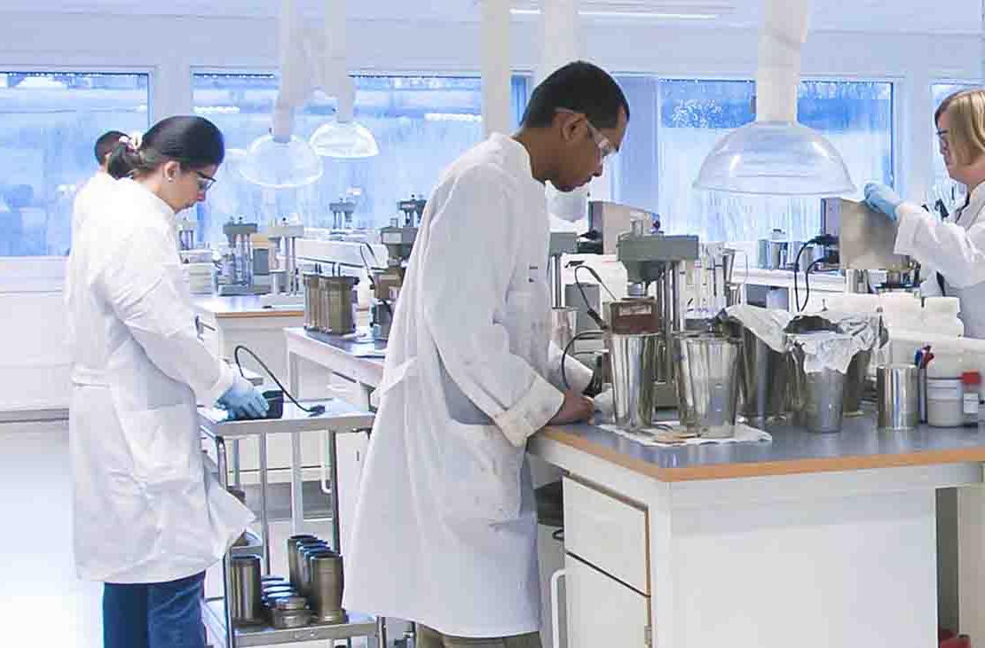 Three people in lab coats in a fluids laboratory.
